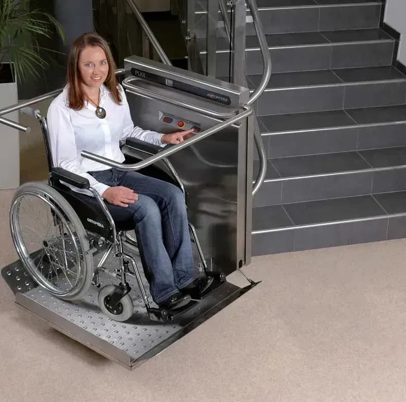 Junge Frau im Rollstuhl auf einem Plattformlift.